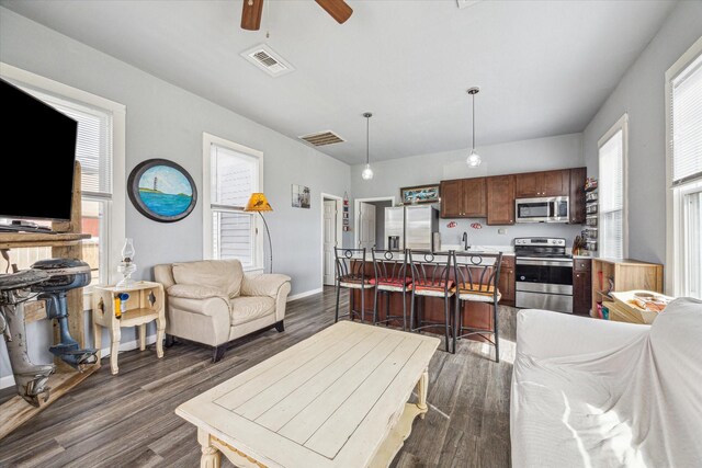 living room with baseboards, visible vents, dark wood-style flooring, and a ceiling fan