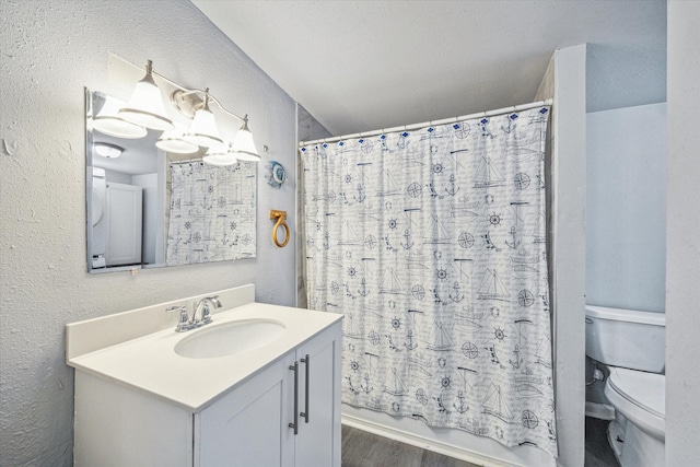 bathroom featuring toilet, a textured wall, wood finished floors, vanity, and shower / bathtub combination with curtain