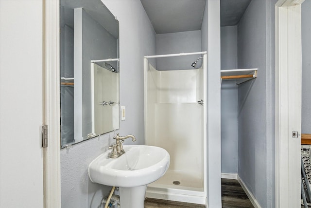 full bathroom featuring baseboards, wood finished floors, and a shower stall