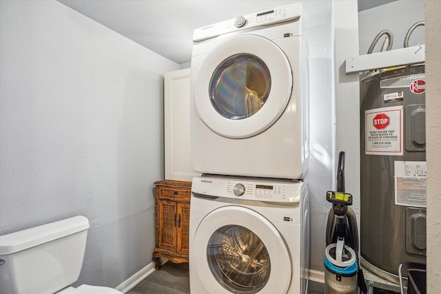 laundry area featuring stacked washer / dryer, laundry area, electric water heater, and baseboards