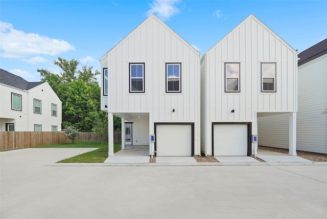 view of front of home featuring board and batten siding, concrete driveway, a garage, and fence