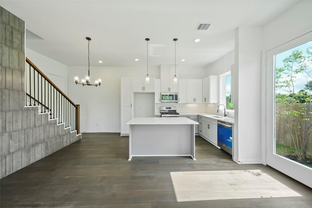 kitchen featuring visible vents, a sink, stainless steel appliances, white cabinets, and a center island