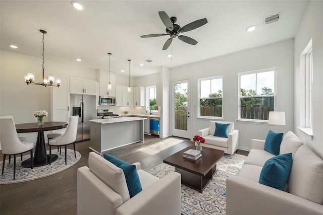 living room featuring recessed lighting, visible vents, dark wood-style flooring, and ceiling fan with notable chandelier