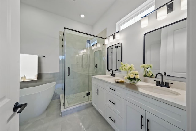 bathroom featuring a sink, a soaking tub, a stall shower, and double vanity