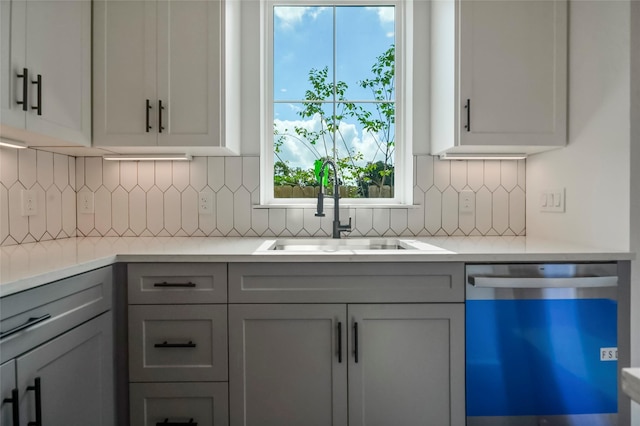 kitchen with tasteful backsplash, gray cabinetry, dishwasher, light countertops, and a sink