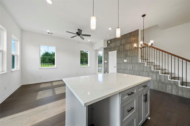 kitchen with open floor plan, pendant lighting, recessed lighting, ceiling fan with notable chandelier, and dark wood-style flooring