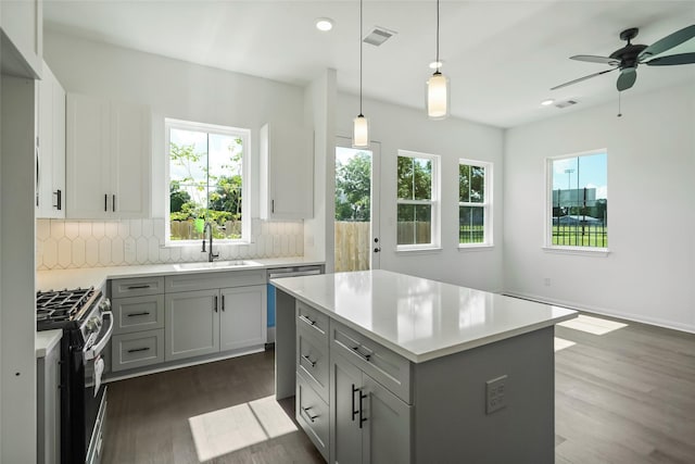 kitchen with a sink, stainless steel gas stove, backsplash, and light countertops