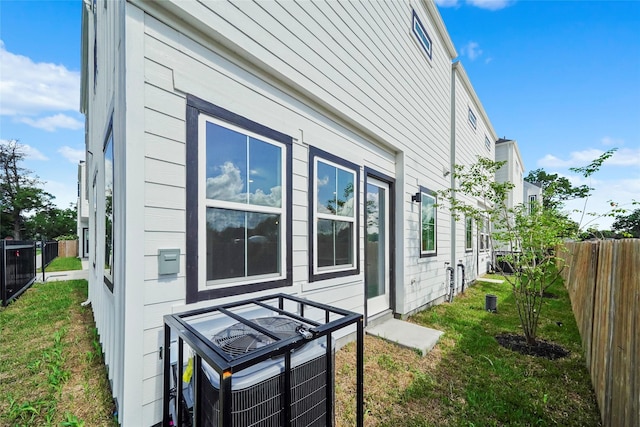 view of side of property with a fenced backyard, central air condition unit, and a yard