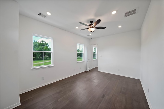 spare room with visible vents, baseboards, dark wood-style floors, and a ceiling fan