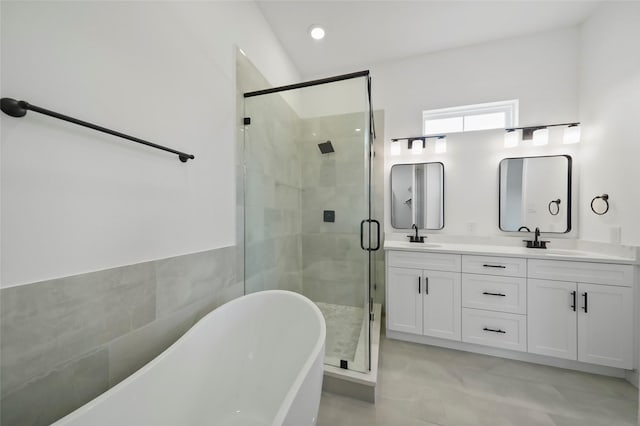 full bath featuring double vanity, a freestanding tub, a shower stall, and a sink