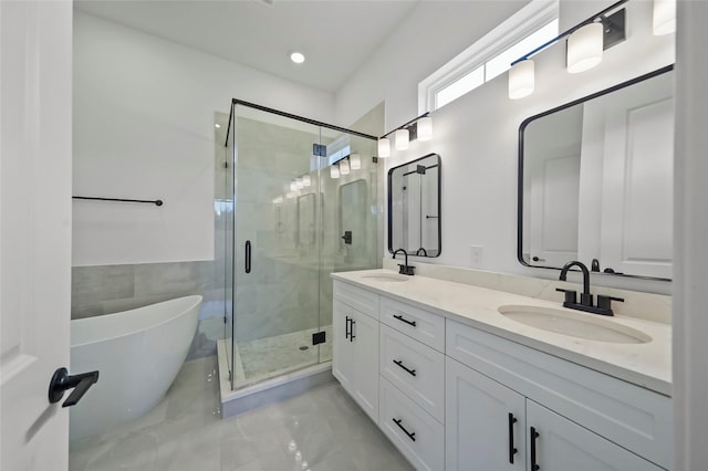 bathroom featuring double vanity, a freestanding tub, a stall shower, and a sink