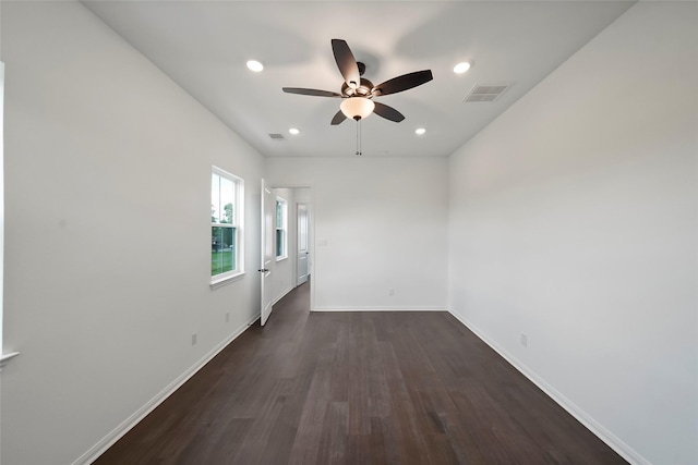 empty room featuring visible vents, baseboards, dark wood-style flooring, and a ceiling fan