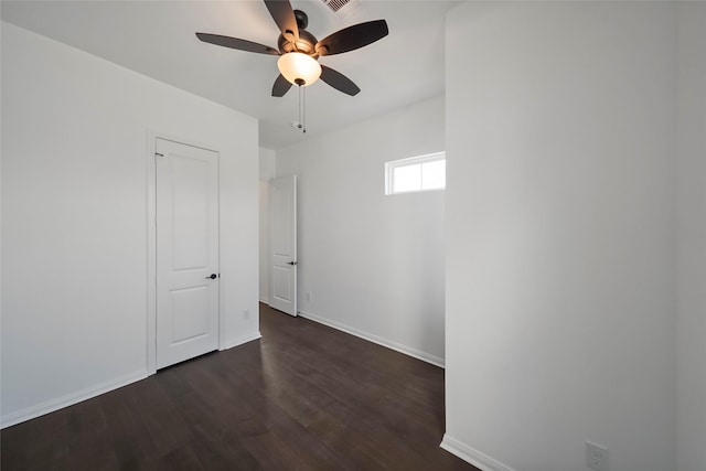 empty room with a ceiling fan, dark wood-style flooring, and baseboards