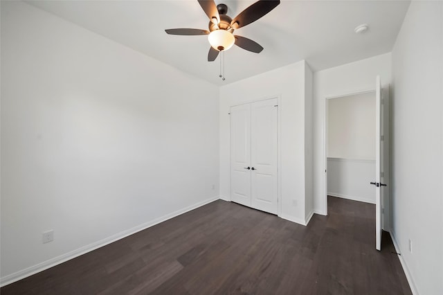 unfurnished bedroom featuring dark wood-style floors, baseboards, a closet, and ceiling fan