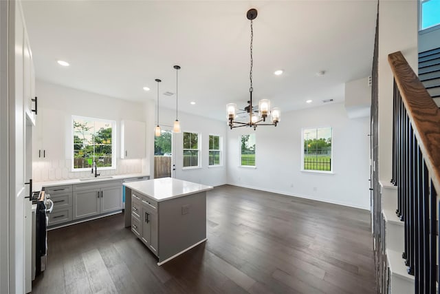 kitchen with a chandelier, dark wood finished floors, decorative backsplash, gray cabinets, and a sink