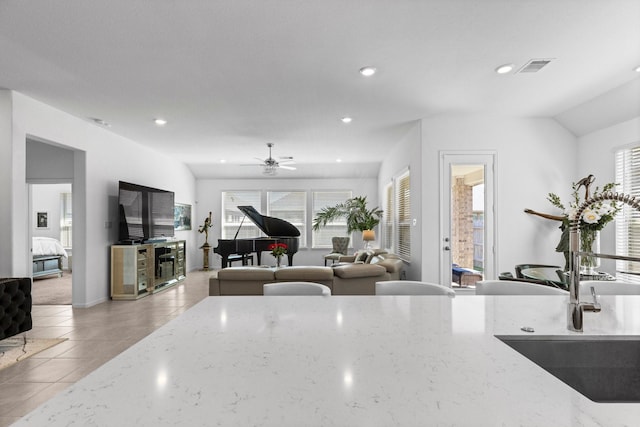 kitchen featuring a ceiling fan, a sink, light stone counters, recessed lighting, and light tile patterned floors