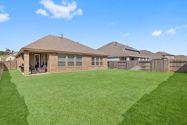 rear view of house with a yard, a patio, brick siding, and a fenced backyard