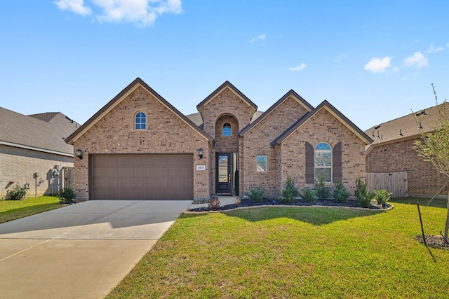 french country home with brick siding, a front lawn, fence, concrete driveway, and a garage