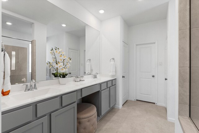 bathroom with double vanity, recessed lighting, a tile shower, a sink, and tile patterned floors