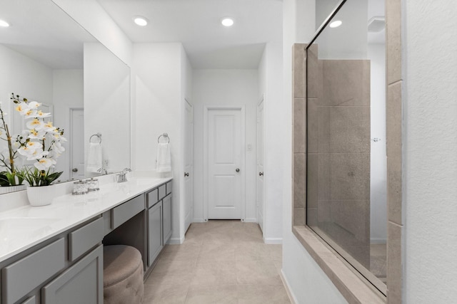 bathroom with baseboards, double vanity, recessed lighting, tiled shower, and tile patterned floors