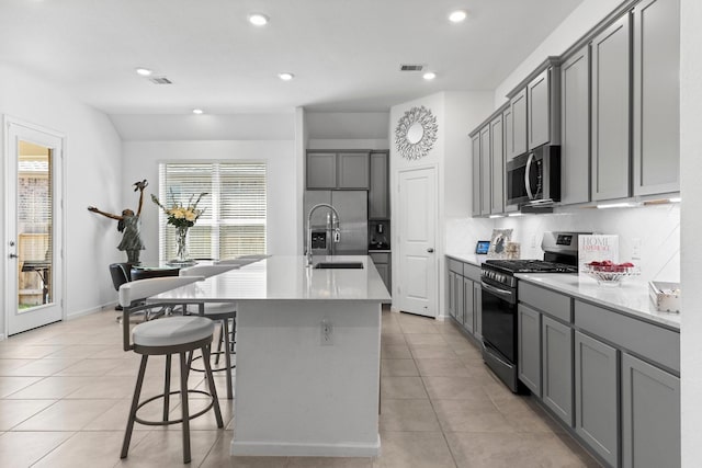 kitchen with visible vents, gray cabinets, a sink, appliances with stainless steel finishes, and light tile patterned floors