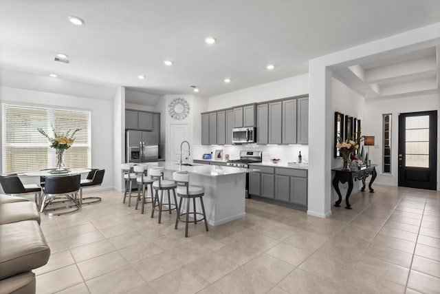 kitchen featuring a kitchen breakfast bar, a healthy amount of sunlight, gray cabinets, and appliances with stainless steel finishes