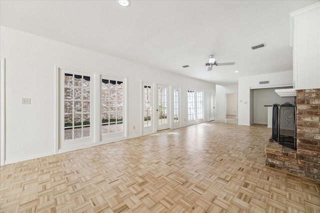 unfurnished living room with visible vents, baseboards, a brick fireplace, and ceiling fan