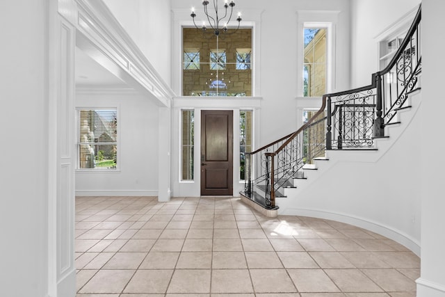 foyer entrance featuring stairway, an inviting chandelier, light tile patterned floors, baseboards, and a towering ceiling