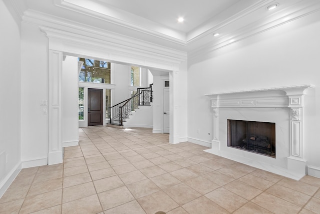 unfurnished living room with stairway, light tile patterned floors, baseboards, a high end fireplace, and ornamental molding