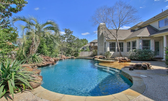 view of swimming pool featuring fence and a pool with connected hot tub