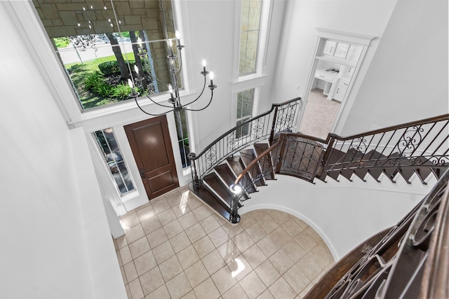 tiled entrance foyer with stairs and a towering ceiling