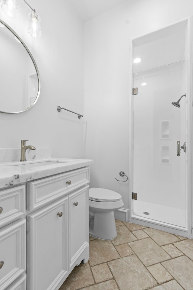 full bath featuring stone tile floors, a shower stall, vanity, and toilet