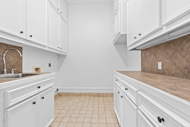 clothes washing area featuring baseboards, washer hookup, cabinet space, hookup for an electric dryer, and a sink