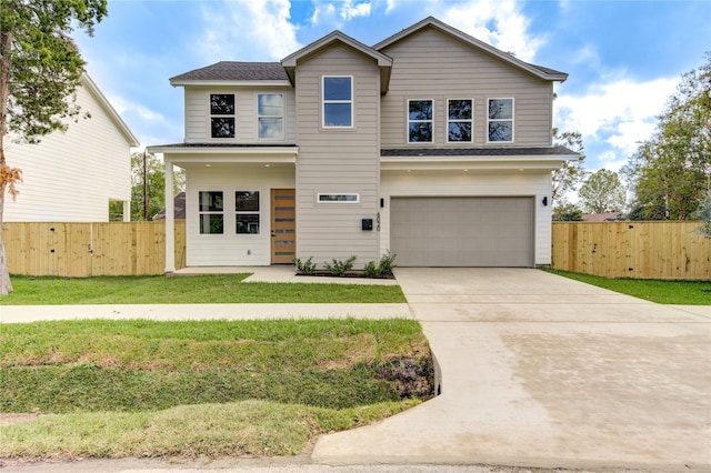 traditional-style house with a front yard, fence, a garage, and driveway