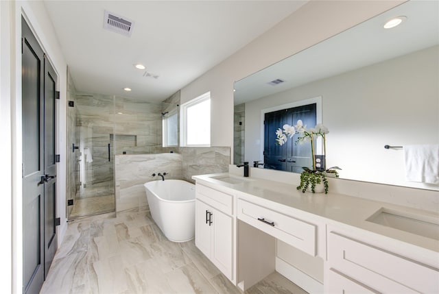 bathroom featuring visible vents, a shower stall, a freestanding bath, double vanity, and a sink