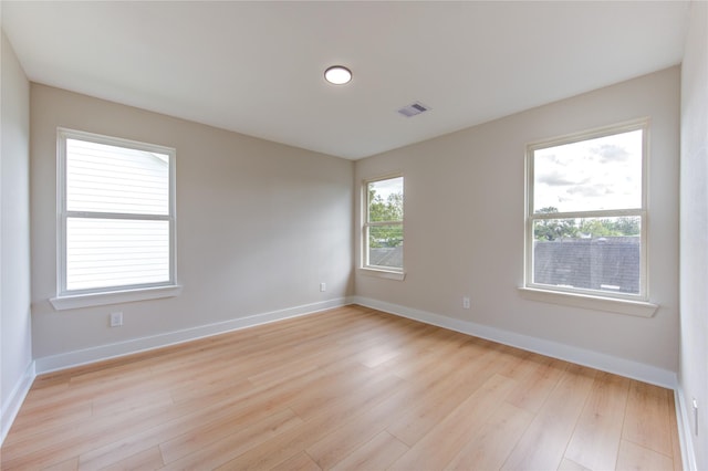 spare room featuring visible vents, light wood-type flooring, and baseboards