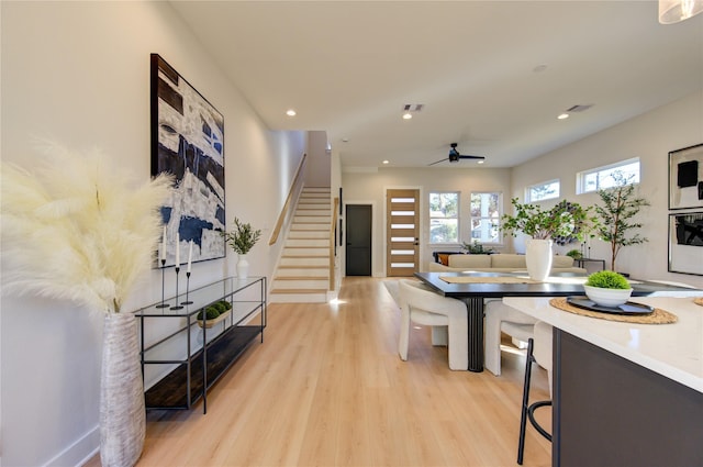 living room featuring stairway, visible vents, a ceiling fan, and light wood-style floors