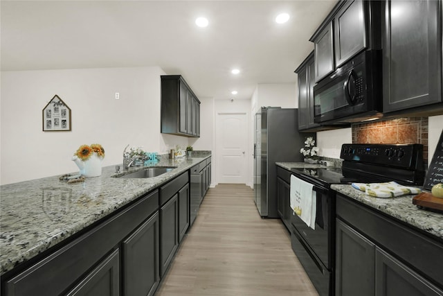 kitchen featuring black appliances, a sink, light wood-style floors, decorative backsplash, and light stone countertops