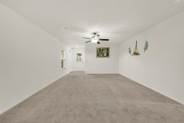 spare room featuring a ceiling fan, light colored carpet, visible vents, and baseboards