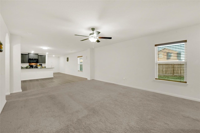 unfurnished living room featuring baseboards, a ceiling fan, and carpet floors