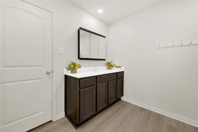 bathroom with vanity, recessed lighting, wood finished floors, and baseboards