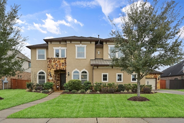 view of front of property with a front yard, fence, a standing seam roof, stucco siding, and a garage