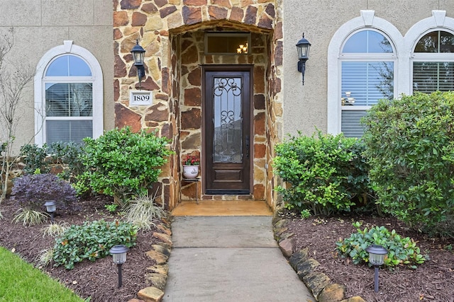 property entrance featuring stone siding and stucco siding