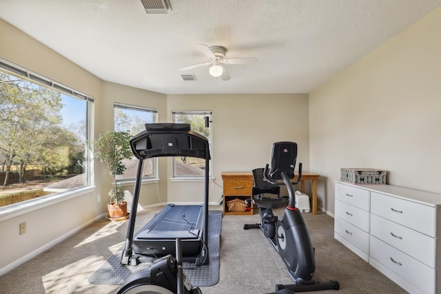 exercise area featuring visible vents, baseboards, a textured ceiling, and ceiling fan