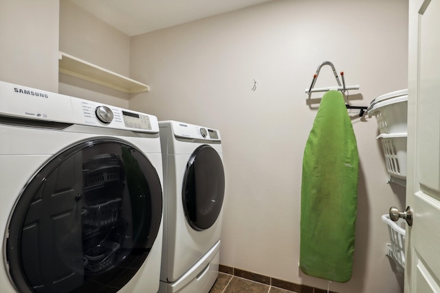 laundry room featuring washer and dryer, baseboards, dark tile patterned floors, and laundry area