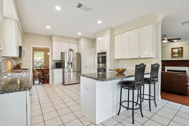 kitchen featuring dark stone countertops, visible vents, light tile patterned flooring, a sink, and stainless steel appliances