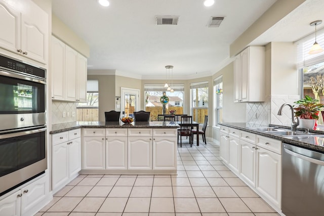 kitchen with visible vents, a peninsula, stainless steel appliances, and a sink