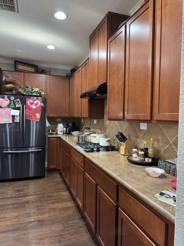 kitchen featuring visible vents, under cabinet range hood, dark wood-style floors, gas stovetop, and freestanding refrigerator