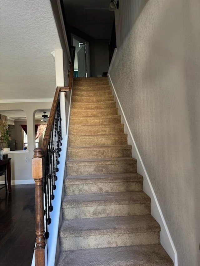 stairs featuring wood finished floors, a textured wall, and a textured ceiling