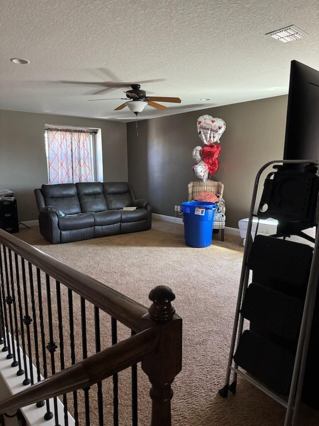 carpeted living area featuring a textured ceiling, visible vents, baseboards, and ceiling fan